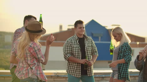 Fife-young-American-people-move-in-a-dance-on-the-party-on-the-roof.-They-have-fun-smile-and-drink-beer.